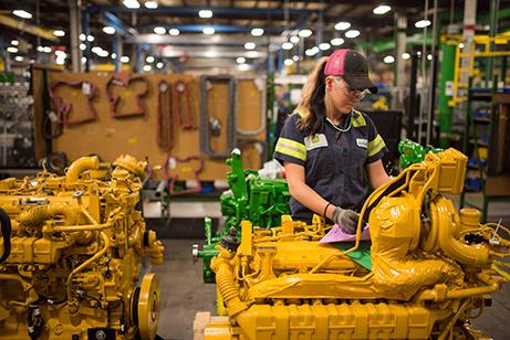 Female working on a yellow machine on the factory floor